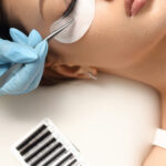 Eyelashes extensions. Fake eyelashes. Eyelash extension procedure.Close up portrait of woman eye with long eyelashes. Professional stylist lengthening female lashes. Master and client in beauty salon.